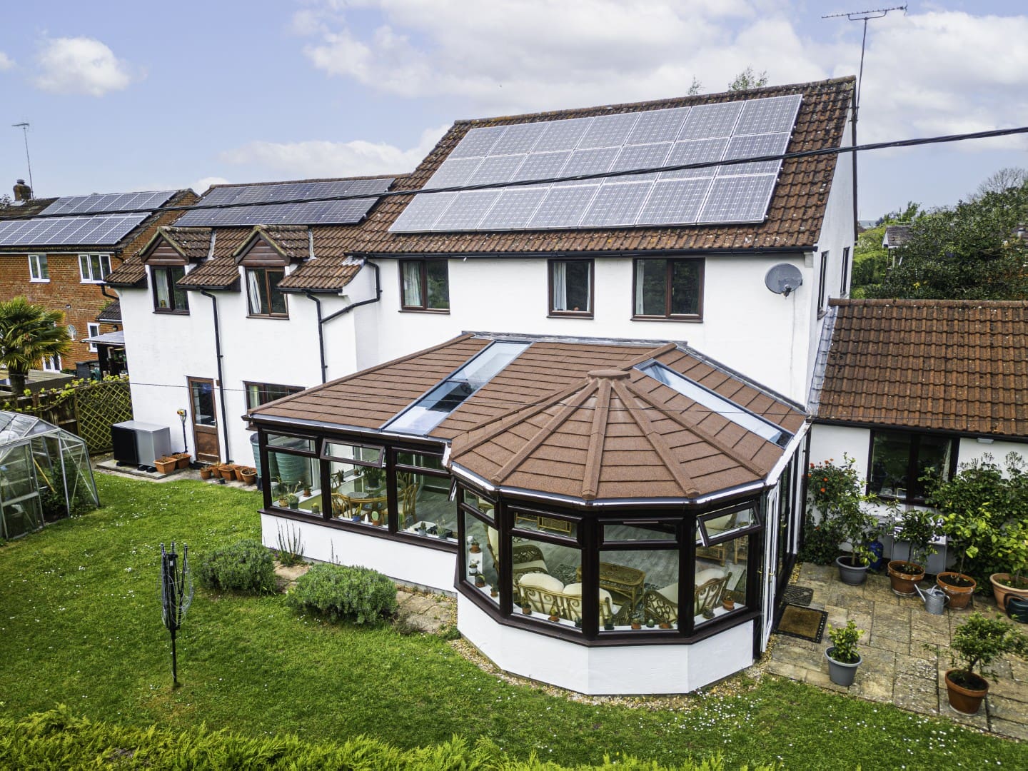 Victorian-style conservatory with a new grey tiled roof on a white house