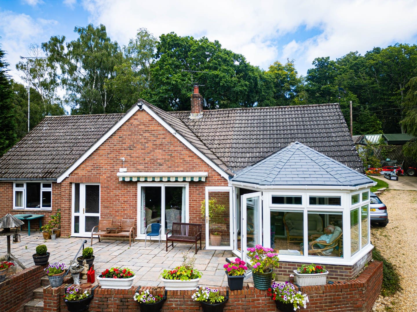 Tiled conservatory roof on a brick bungalow with a flower-filled front garden