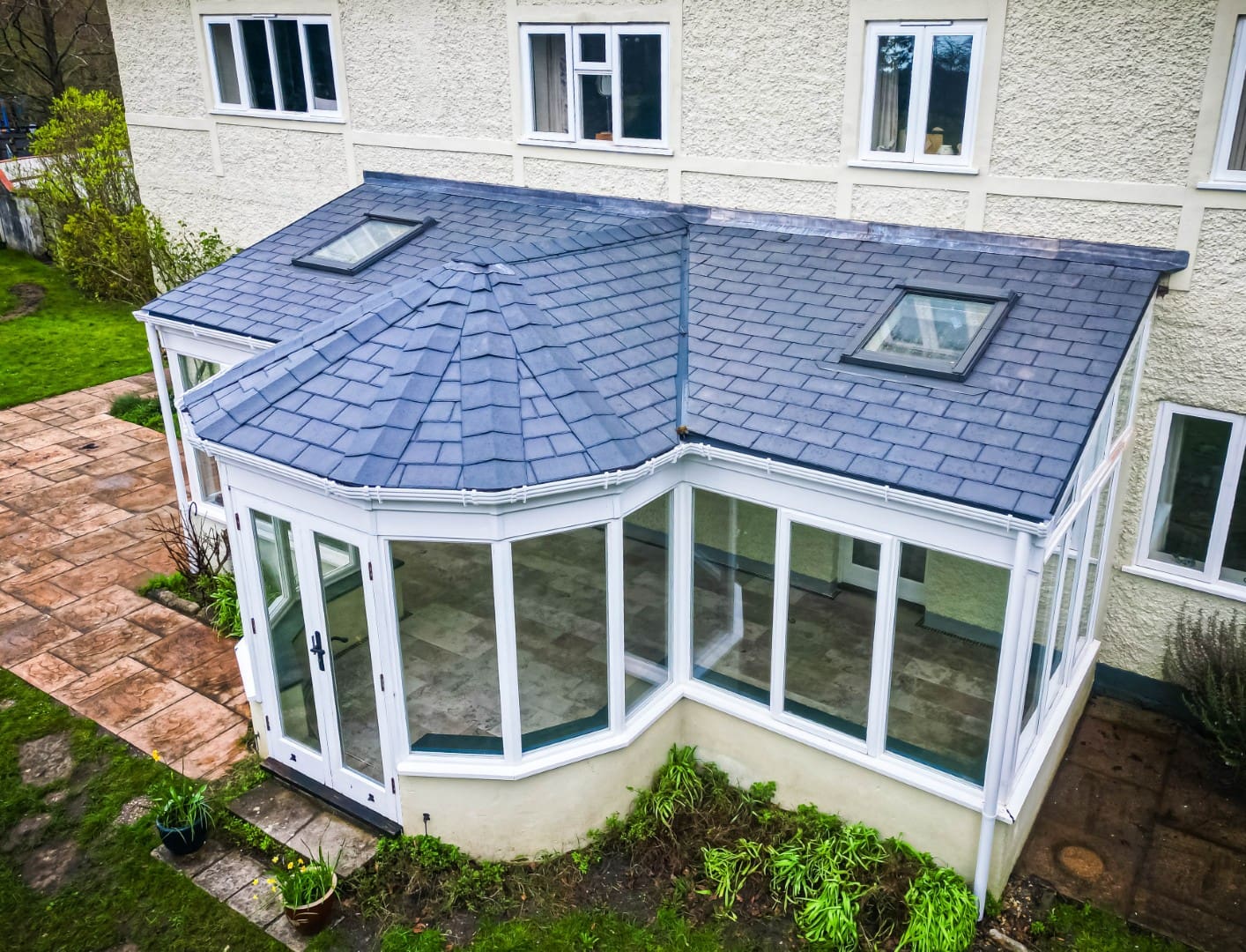 P-shaped conservatory with a grey tiled roof and roof window