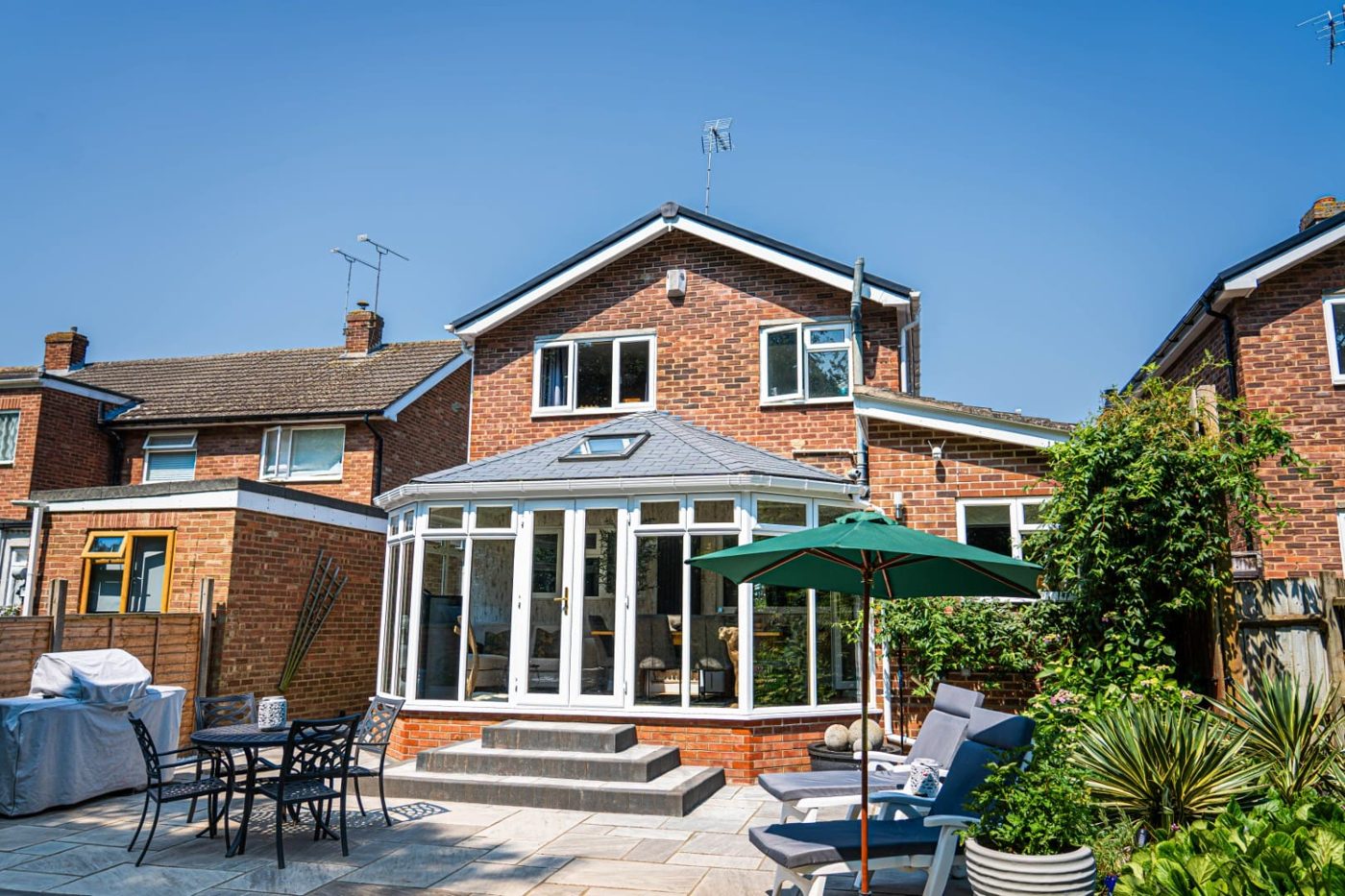 Tiled conservatory roof over a patio with garden furniture