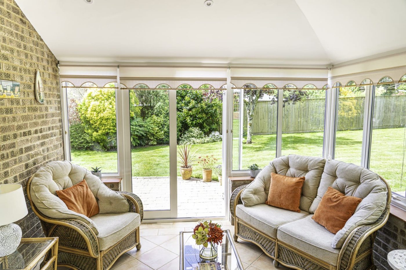 Inside a tiled-roof conservatory with a plastered ceiling and garden view