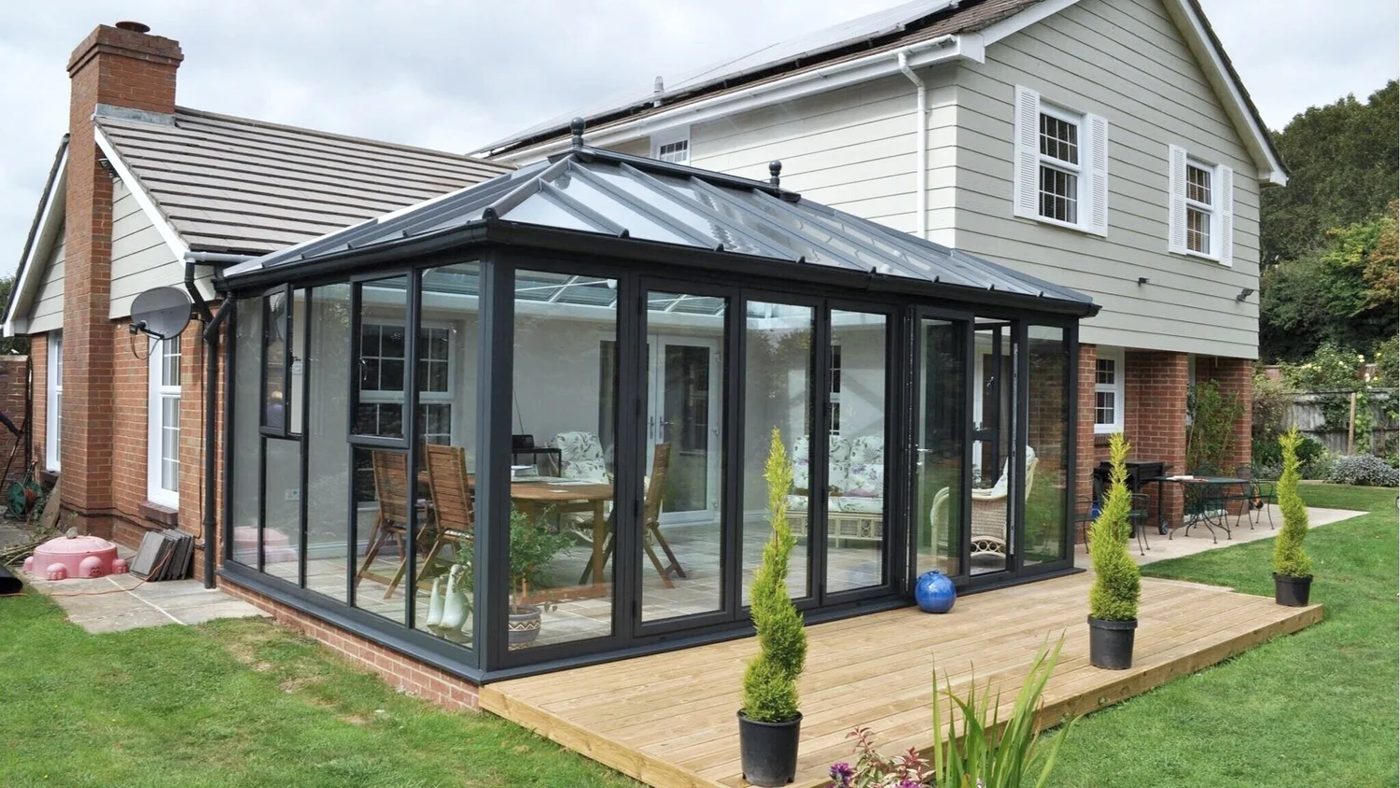 Glass conservatory roof in anthracite grey with matching frames and decking